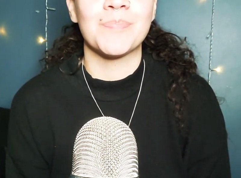 "Mad Gremlin" Asmr wearing a black outfit in front of a microphone.