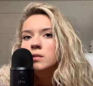 "Sadie's Asmr" face selfie in front of a microphone.