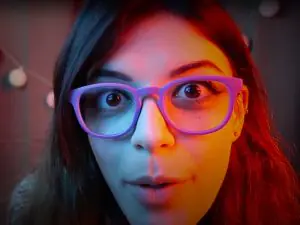 "Harley Quinn ASMR" with purple glasses up close face picture.