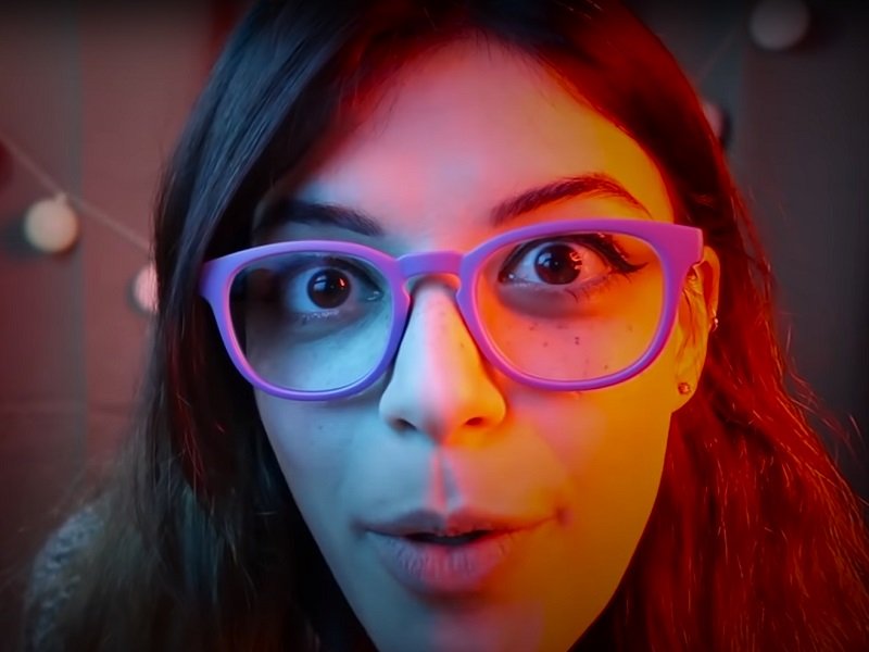 "Harley Quinn ASMR" with purple glasses up close face picture.